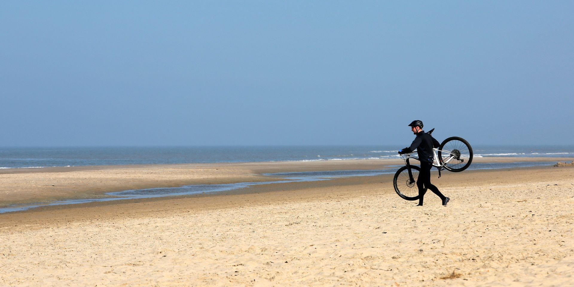 Fietser met mountainbike op het strand met zee uitzicht
